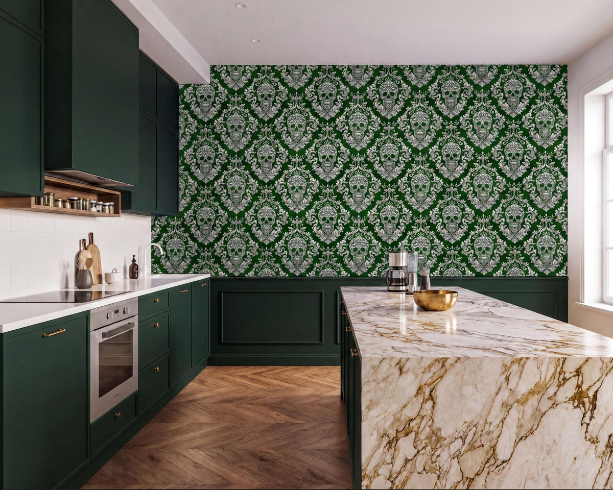 a modern kitchen with a large marble countertop and dark green cabinets. The walls are covered in a green and white damask pattern, creating a striking contrast with the marble countertop. The kitchen features a large island with a gold bowl on it, and a stainless steel oven is visible on the left side of the image.