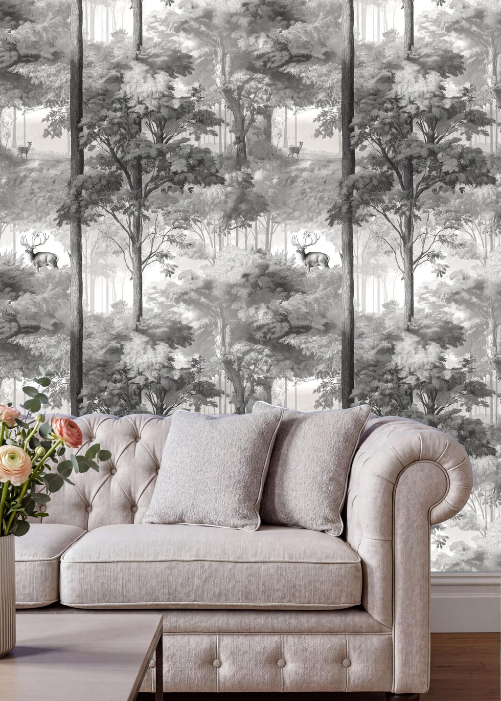 a living room with a white tufted sofa and a vase of flowers on a coffee table. The sofa is positioned against a wall with a black and white forest wallpaper.