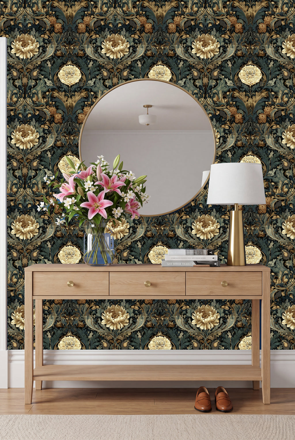 a wooden console table with a round mirror above it, set against a wall with a floral wallpaper. The table has a vase of pink flowers and a lamp on it.