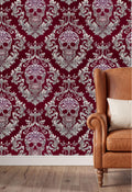 a red wall with a repeating pattern of white skulls and floral designs, creating a striking and bold visual effect. In the foreground, there is a brown leather armchair with a white pillow on it, providing a cozy and inviting atmosphere.