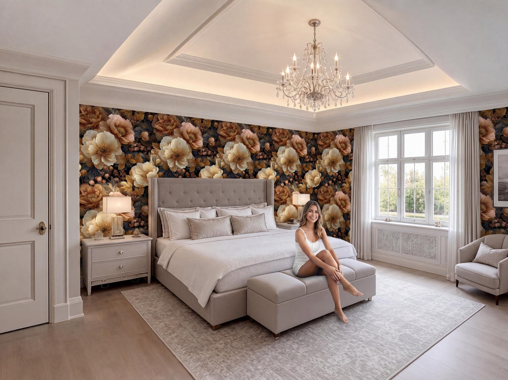 A woman sits on a bench in a luxurious bedroom with a large bed, floral wallpaper, and a chandelier overhead.