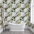 a bathroom with a white clawfoot bathtub in the center, surrounded by a floral wallpaper with white hydrangeas and green leaves. A wooden ladder is leaning against the wall next to the bathtub.