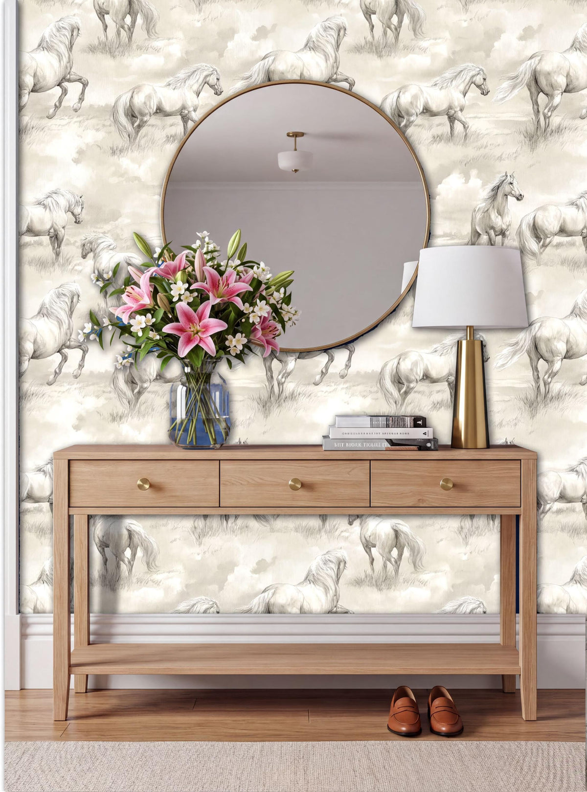 a wooden console table with a round mirror above it, a vase of pink flowers, and a lamp on the table. The wall behind the table has a wallpaper with a horse pattern.