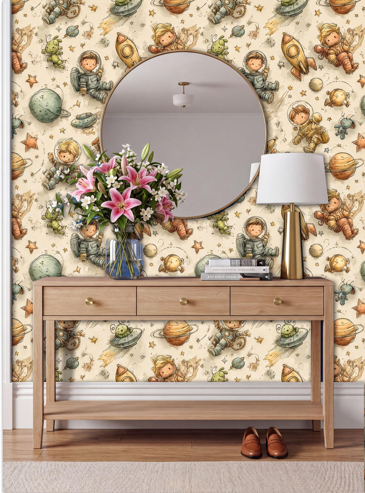 a wooden console table with a round mirror above it, set against a wall with a space-themed wallpaper. The table has a vase of pink flowers and a lamp on it.