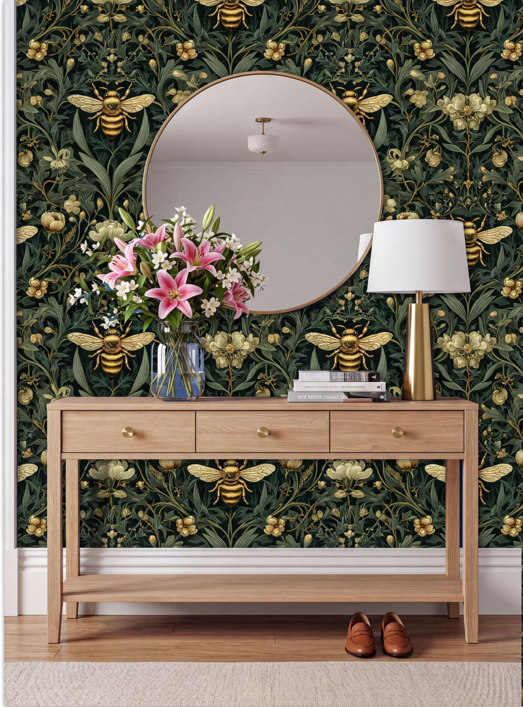 a wooden console table with a vase of pink flowers, a round mirror, a lamp, and a pair of brown shoes placed on a rug. The wall behind the table has a green and gold floral wallpaper with a bee motif.