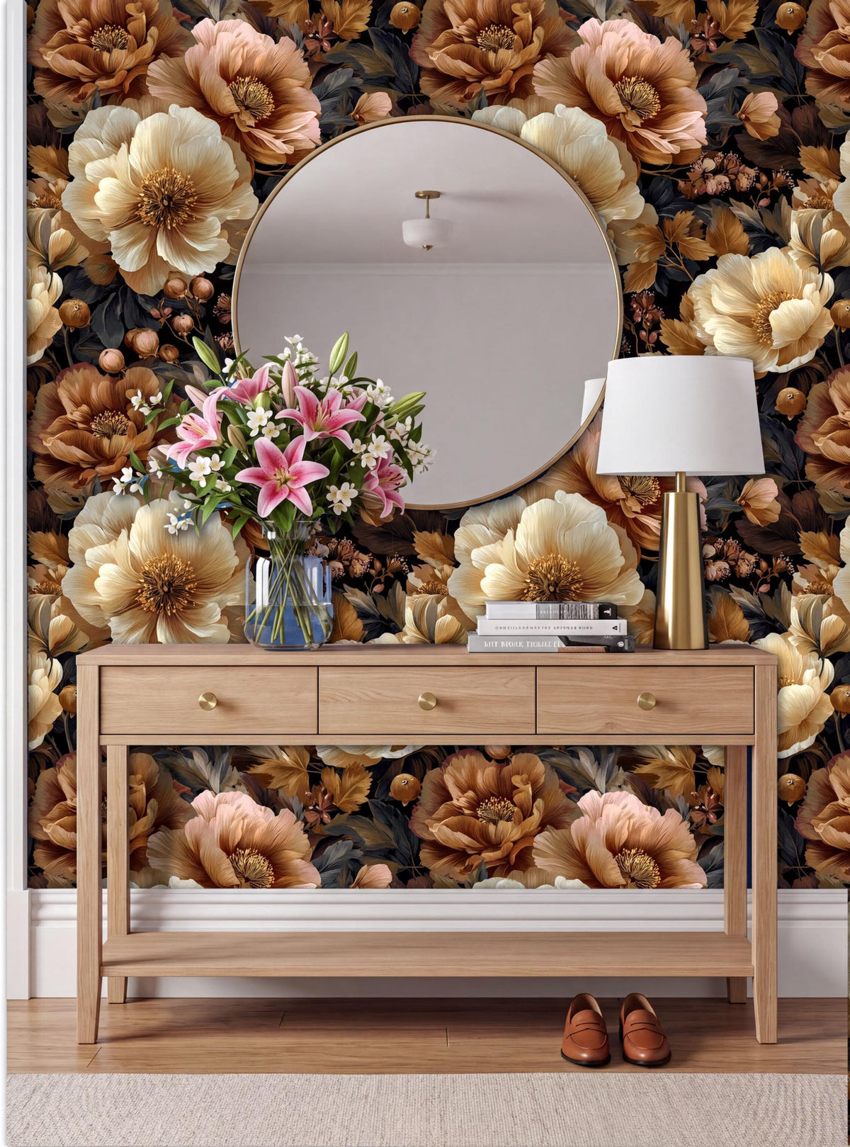 a wooden console table with a round mirror above it, set against a wall with a floral wallpaper. The table has a vase of flowers and a lamp on it, creating a cozy and inviting atmosphere.