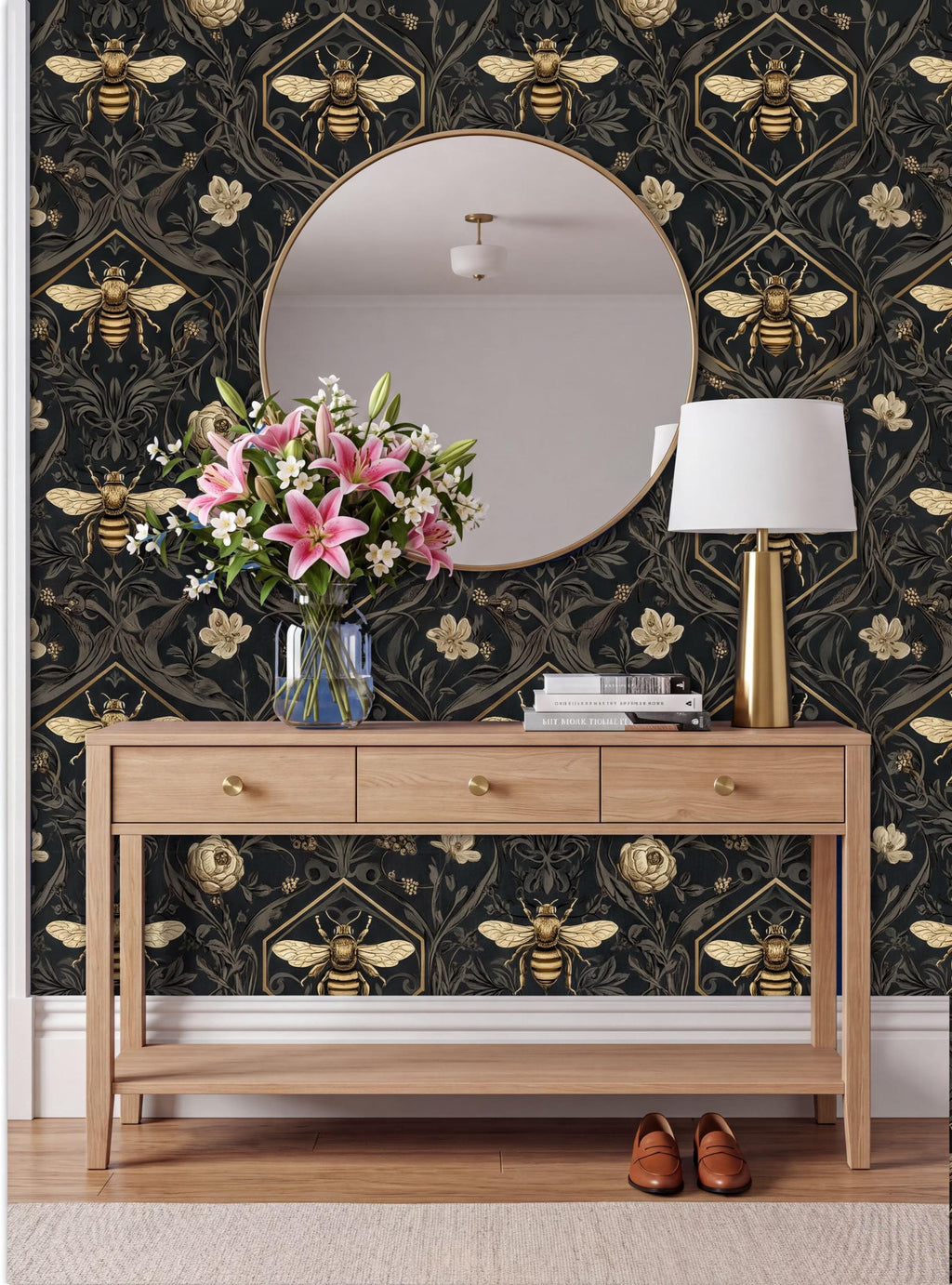 a wooden console table with a vase of pink flowers, a round mirror, a lamp, and a pair of brown shoes placed on a rug. The wall behind the table has a black and gold bee and flower pattern.