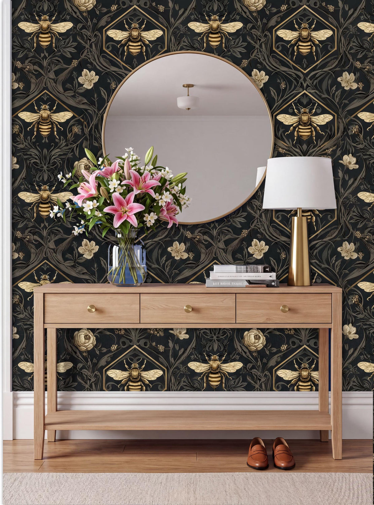 a wooden console table with a vase of pink flowers, a round mirror, a lamp, and a pair of brown shoes placed on a rug. The wall behind the table has a black and gold bee and flower pattern.