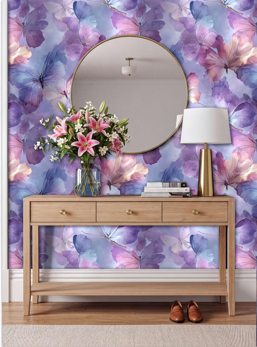 a wooden console table with a round mirror above it, set against a vibrant purple and blue floral wallpaper. The table has three drawers and a lamp on it. A vase of pink flowers is placed on the table, and a pair of brown shoes can be seen on the floor next to the table.