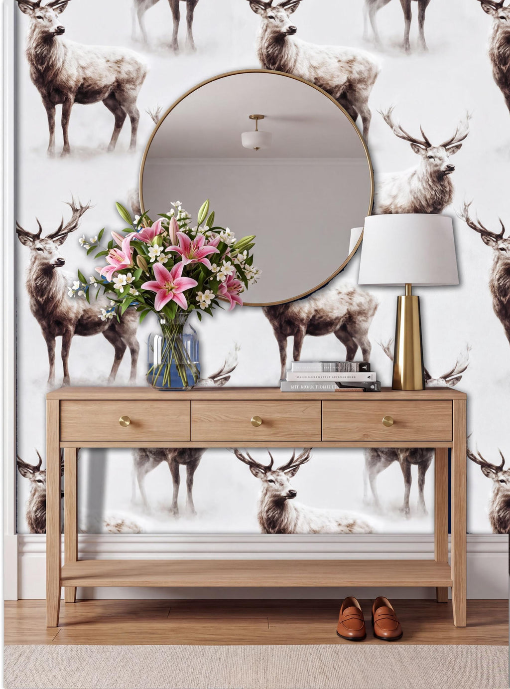 a wooden console table with a round mirror above it, and a vase of pink flowers on the table. The wall behind the table has a repeating pattern of deer images.