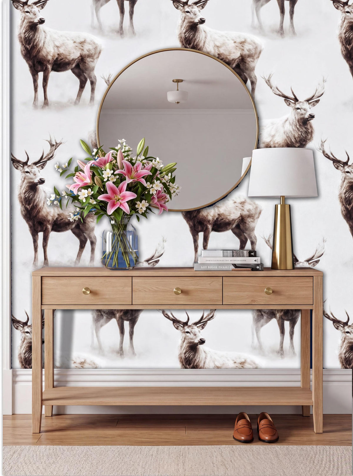 a wooden console table with a round mirror above it, and a vase of pink flowers on the table. The wall behind the table has a repeating pattern of deer images.
