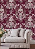 a living room with a white tufted sofa and a coffee table. The sofa is positioned against a wall with a repeating pattern of skull designs in shades of red and white, creating a striking and bold visual effect. The coffee table is placed in front of the sofa, adding to the room's cozy and inviting atmosphere.