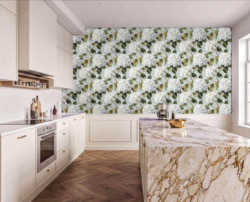 a modern kitchen with a marble countertop and a large wall mural featuring white hydrangea flowers. The kitchen has white cabinets and a wooden floor, creating a clean and elegant atmosphere.