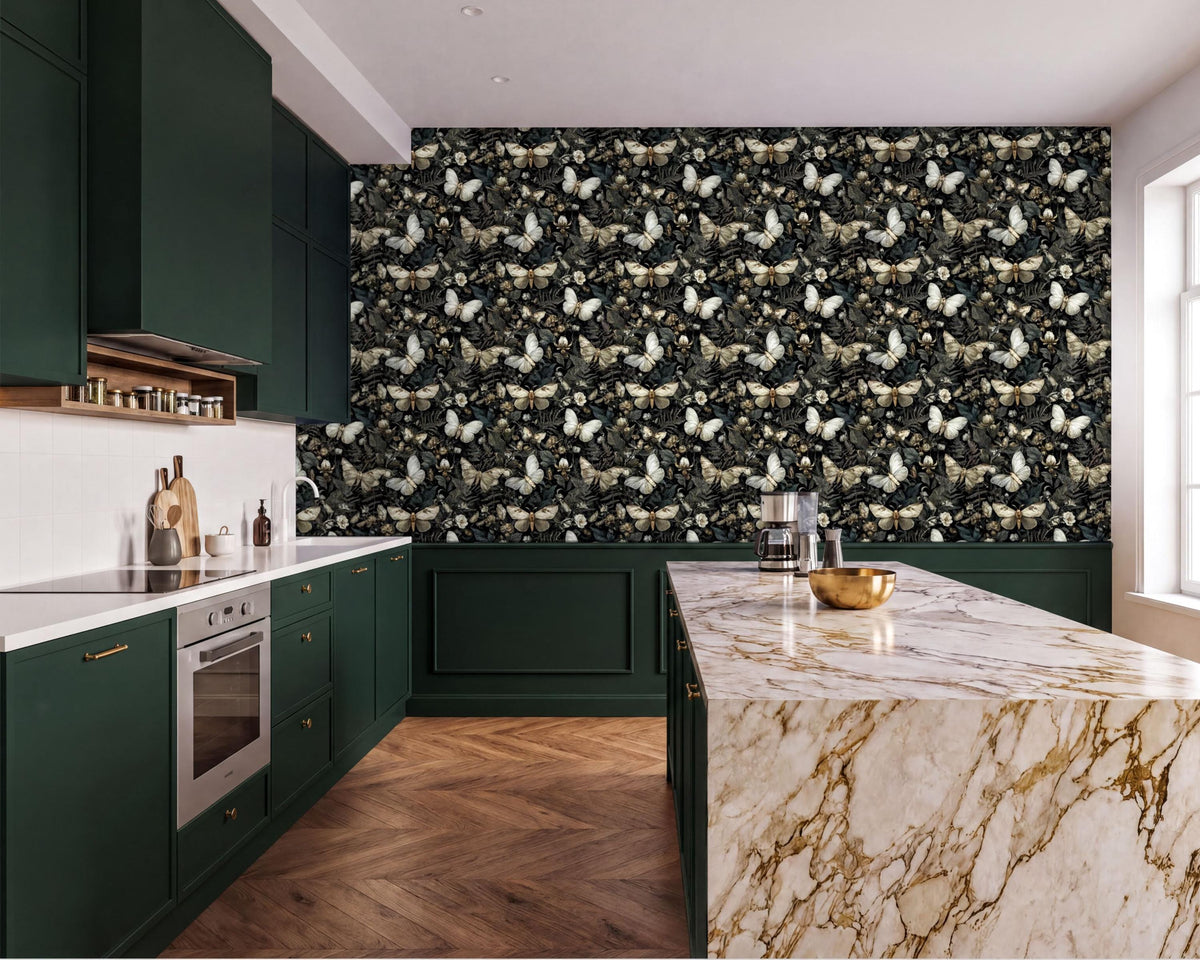a modern kitchen with a marble countertop and dark green cabinets. The walls are covered in a black and white butterfly wallpaper, creating a striking contrast with the marble surface. The kitchen features a large island with a gold bowl on it, and a stainless steel oven is visible on the left side of the room.