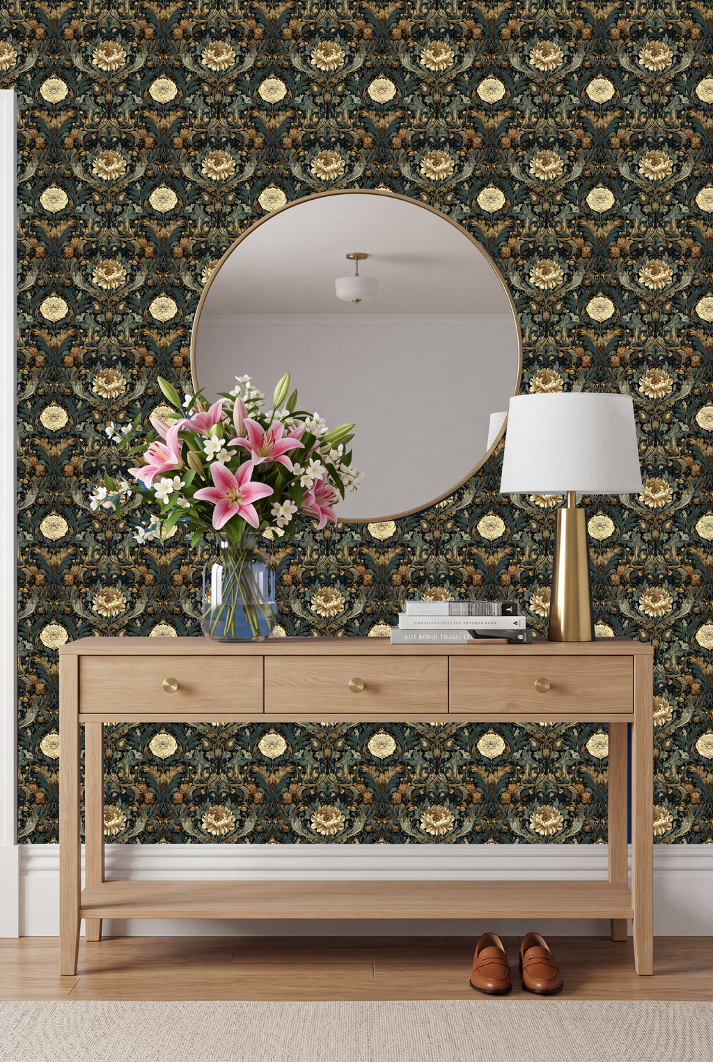 a wooden console table with a vase of pink lilies and a round mirror above it, set against a wall with a floral wallpaper.
