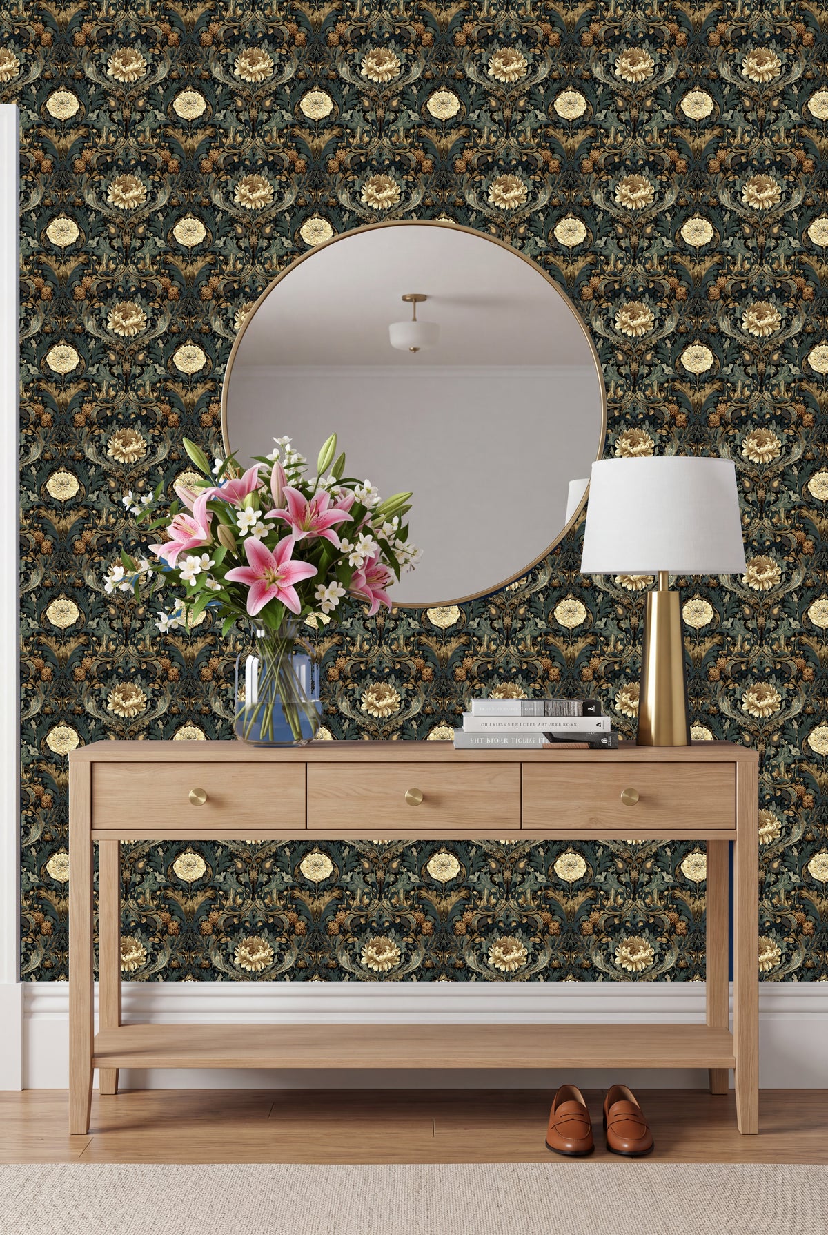 a wooden console table with a vase of pink lilies and a round mirror above it, set against a wall with a floral wallpaper.
