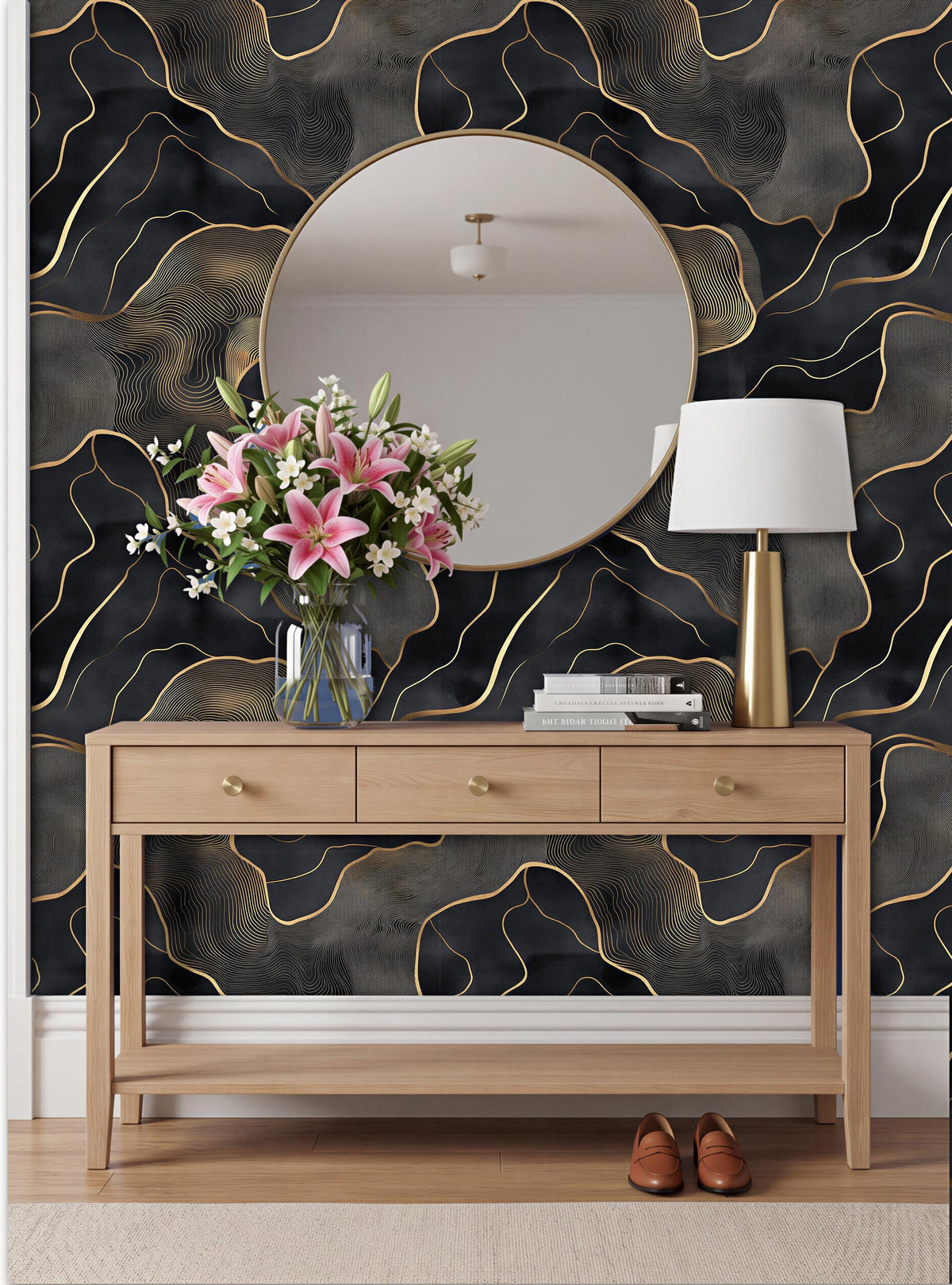 a modern interior design with a wooden console table, a round mirror, a vase of pink flowers, and a lamp. The wall behind the table has a black and gold abstract pattern.