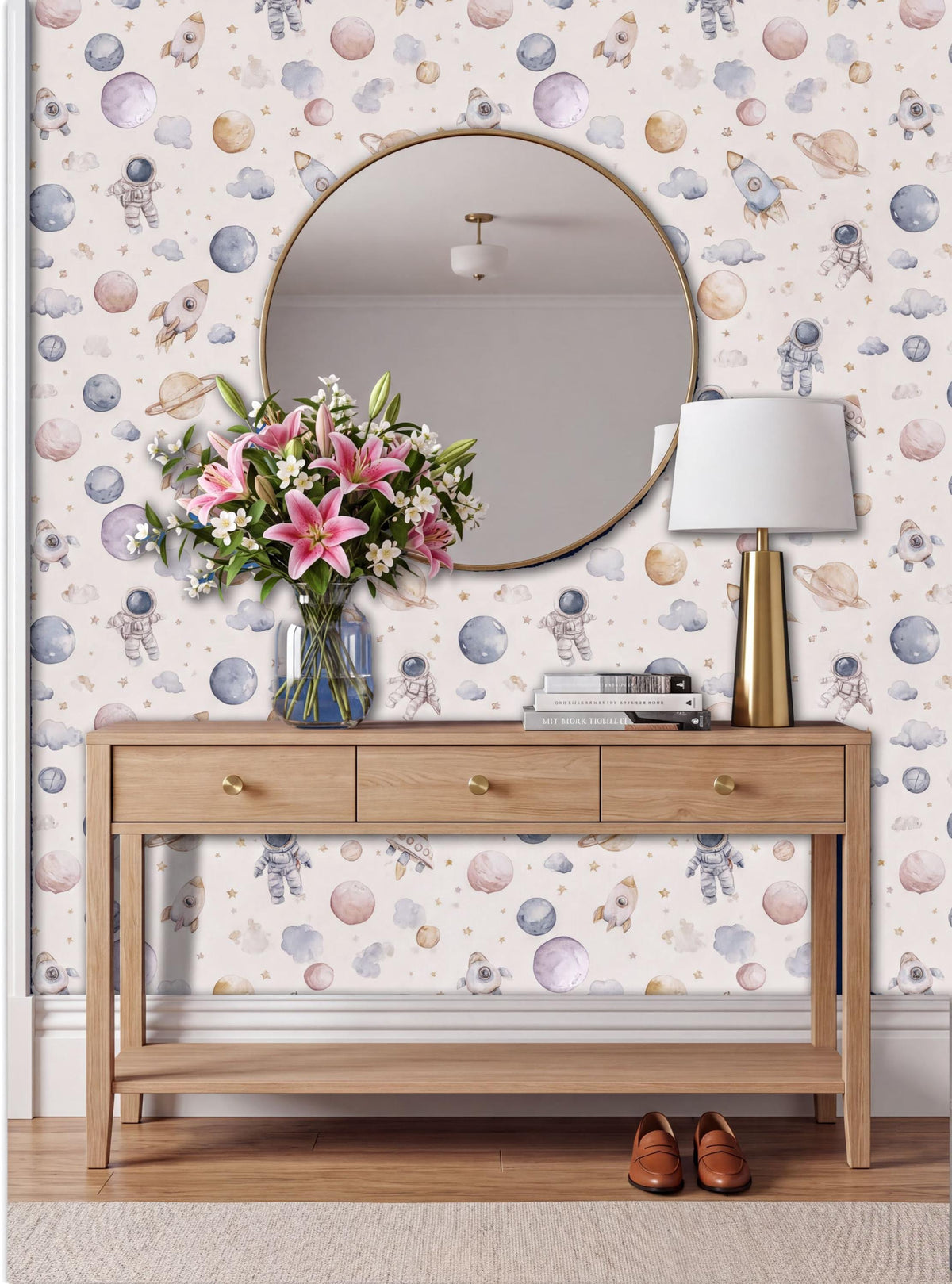 a wooden console table with a round mirror above it, a vase of pink flowers, a lamp, and a pair of brown shoes placed on the floor.