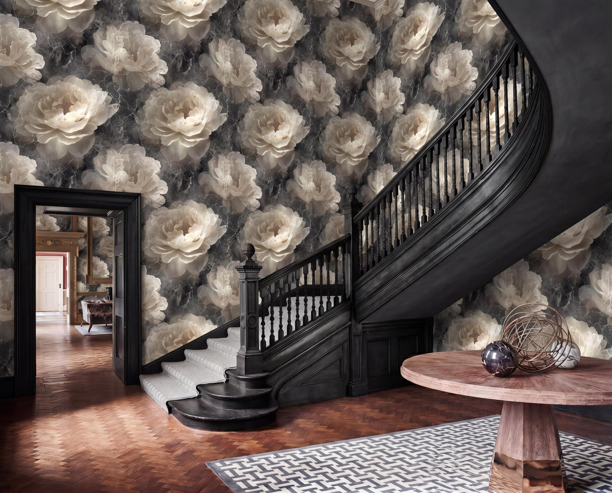 a grand staircase with a black railing and a wooden table on the steps, set against a wall with a floral pattern in shades of gray and white.