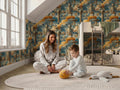 A woman and a young boy are sitting on the floor in a bedroom, playing with a stuffed animal.