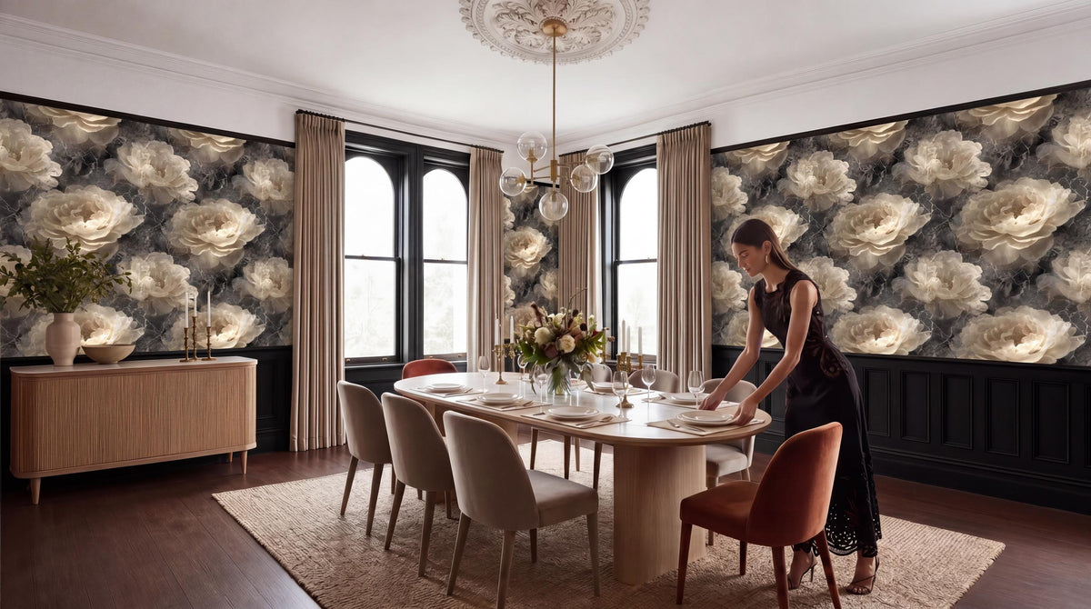 A woman in a black dress is setting the table in a dining room with a large floral wallpaper, a chandelier, and a wooden table with chairs.