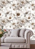 a living room with a gray tufted sofa and a vase of flowers on a coffee table. The sofa is positioned against a wall with a floral wallpaper pattern.