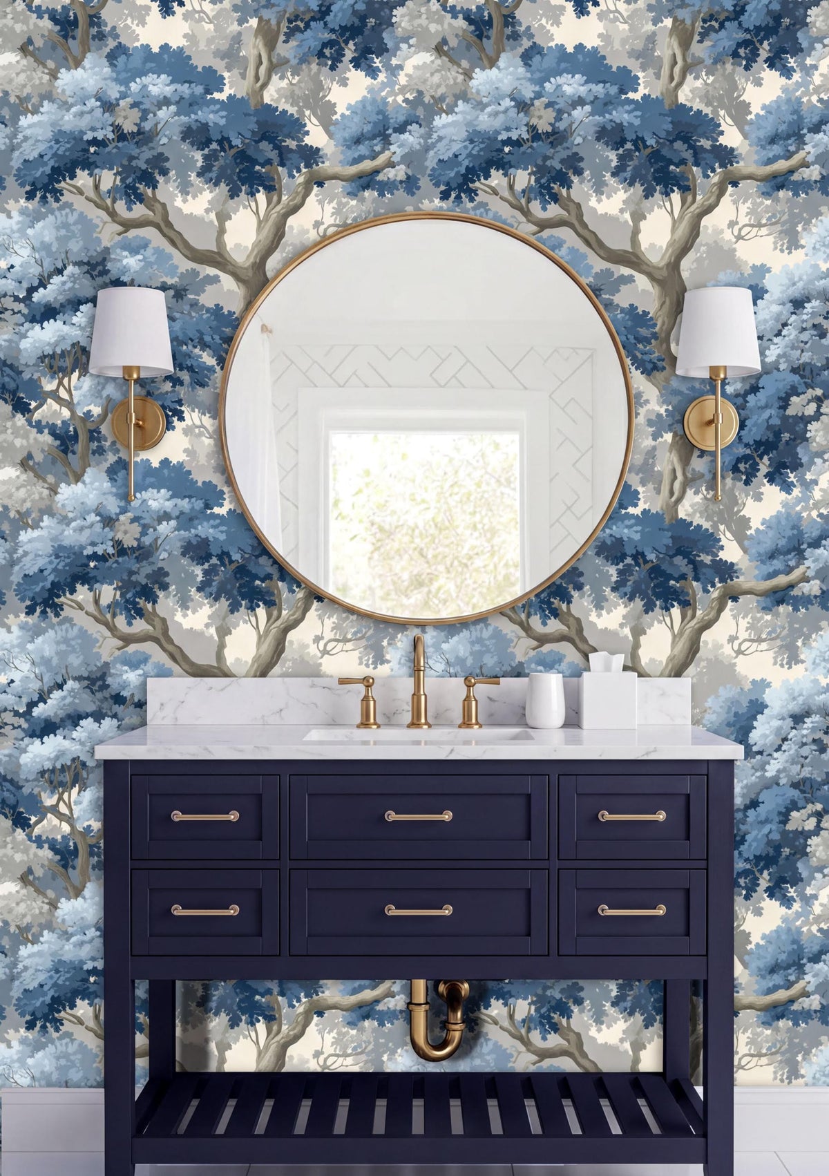 a bathroom vanity with a round mirror, a white countertop, and two wall sconces. The vanity is painted in a dark blue color and has gold hardware. The wall behind the vanity is covered in a blue and white wallpaper with a tree-like pattern.