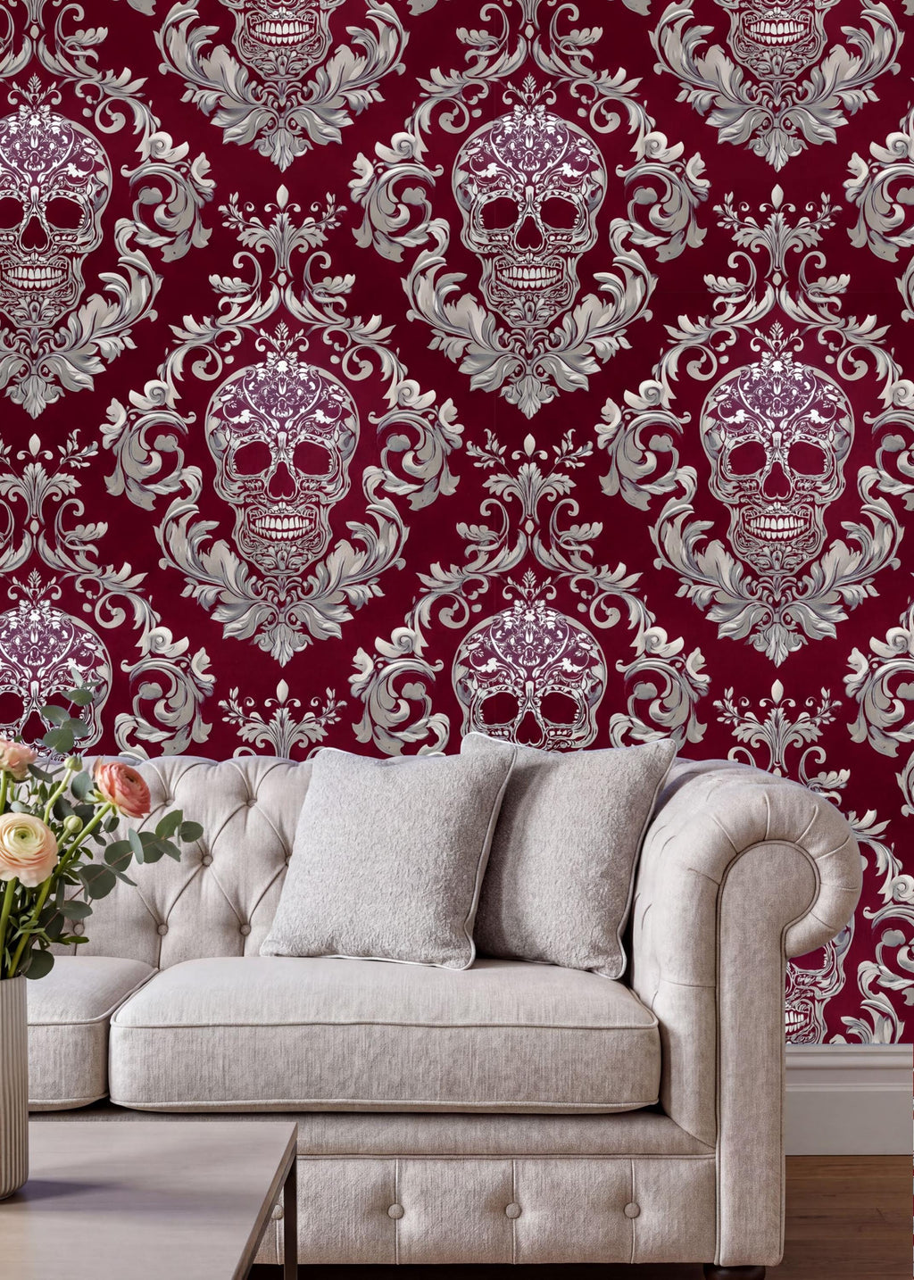 a living room with a white tufted sofa and a coffee table. The sofa is positioned against a wall with a red and white damask pattern, which includes a repeating design of skulls and floral elements. The coffee table is placed in front of the sofa, and there is a vase of flowers on the table.
