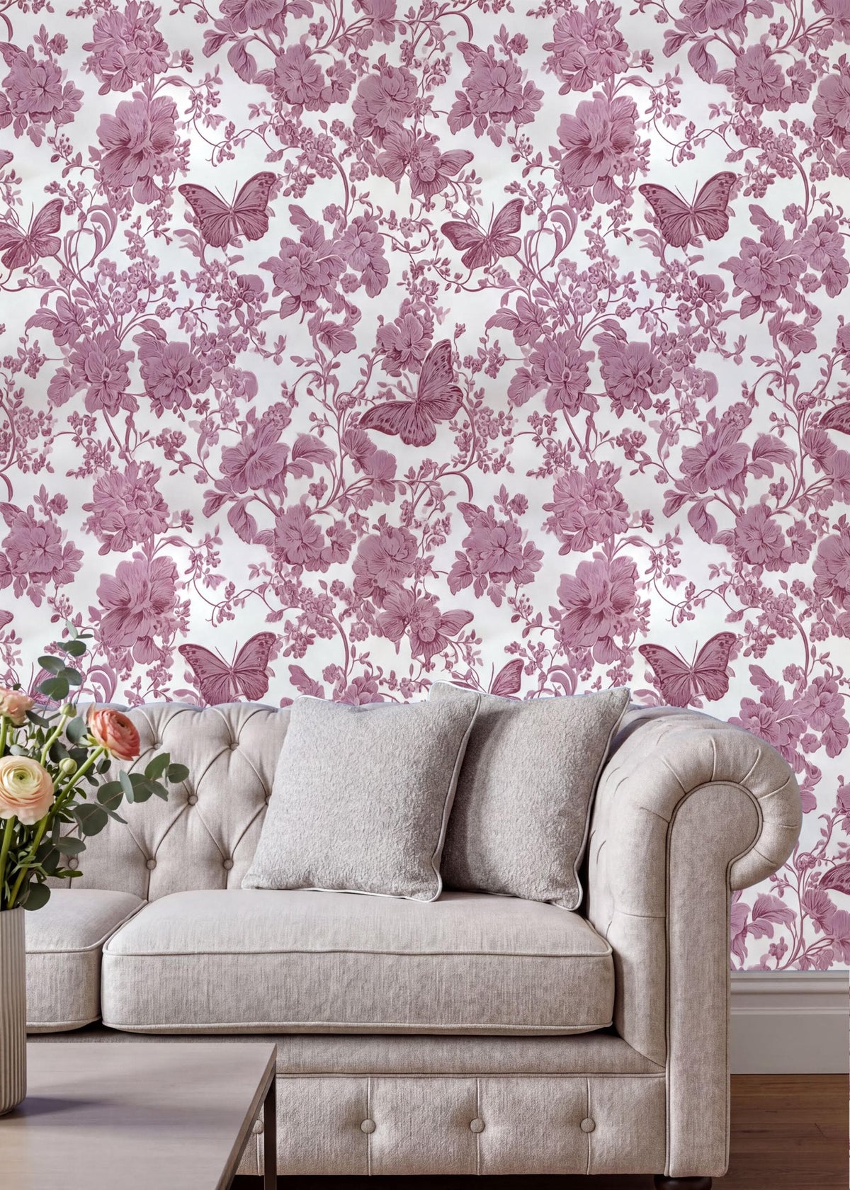a living room with a white sofa and a vase of flowers on a table. The wall behind the sofa is covered in a floral wallpaper with pink flowers and butterflies.