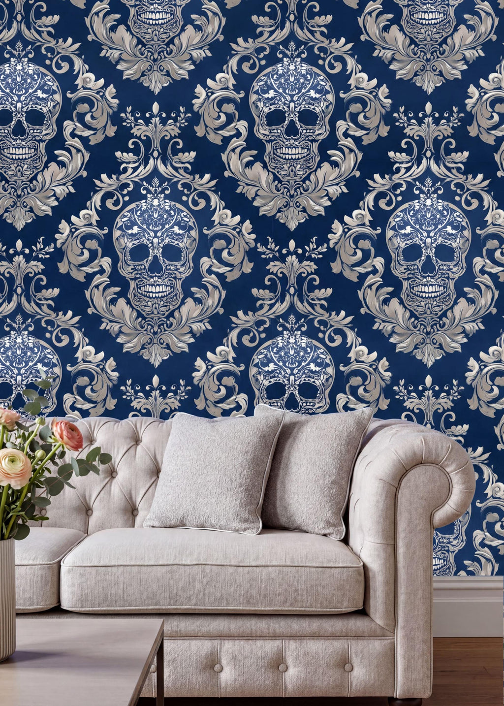 a living room with a white tufted sofa and a coffee table. The sofa is positioned against a wall with a blue and white damask pattern, which includes a repeating pattern of skull designs. The coffee table is placed in front of the sofa, creating a cozy and inviting seating area.
