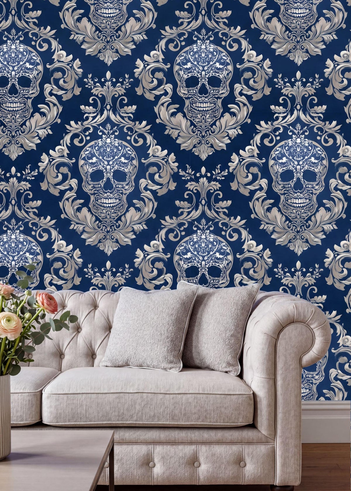 a living room with a white tufted sofa and a coffee table. The sofa is positioned against a wall with a blue and white damask pattern, which includes a repeating pattern of skull designs. The coffee table is placed in front of the sofa, creating a cozy and inviting seating area.